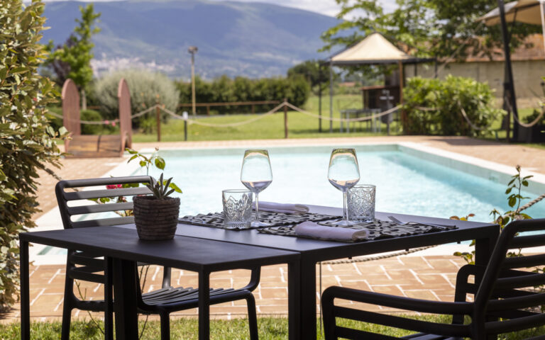 Tavolo allestito con calici e bicchieri accanto alla piscina dell'osteria favorita