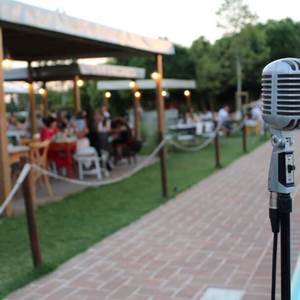 Microfono davanti alla piscina della Favorita con pubblico seduto per evento musicale estivo a Bastia Umbra
