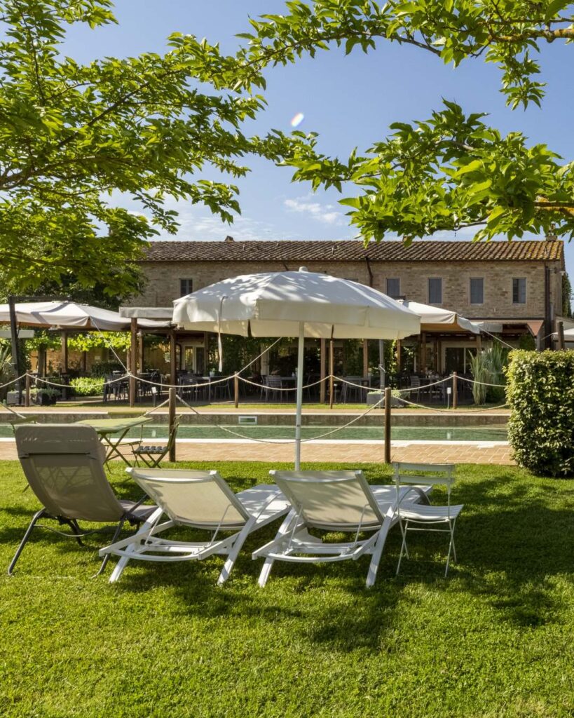Lettini e ombrellone nel giardino dell’Osteria Favorita con vista sulla piscina durante la giornata di Ferragosto