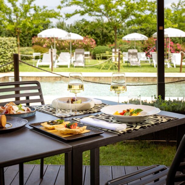 Piatti estivi e calici di vino serviti a bordo piscina all’Osteria Favorita a Ferragosto 2025
