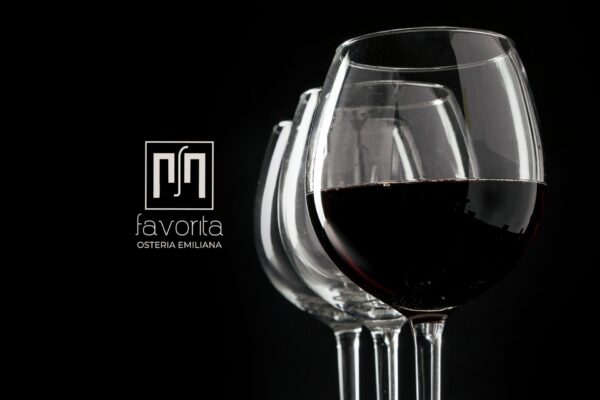 Calici di vino rosso su sfondo nero con logo Osteria Favorita – immagine simbolo della serata Vini Veri 2026